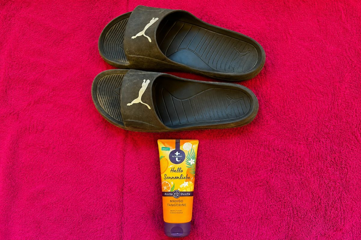 Meine schwarzen Badesandalen auf einem roten Handtuch