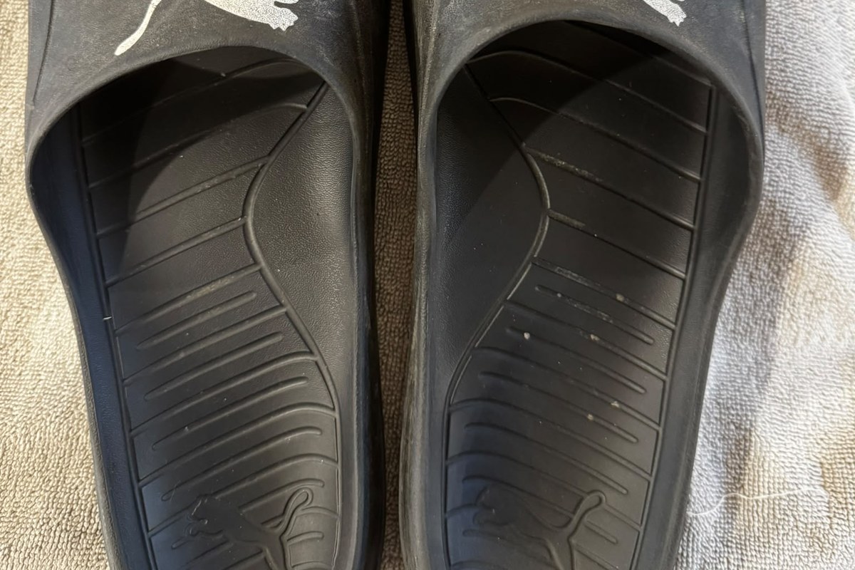 Nahaufnahme der Fußbetten und Riemen schwarzer Badeschuhe auf einem hellen Handtuch