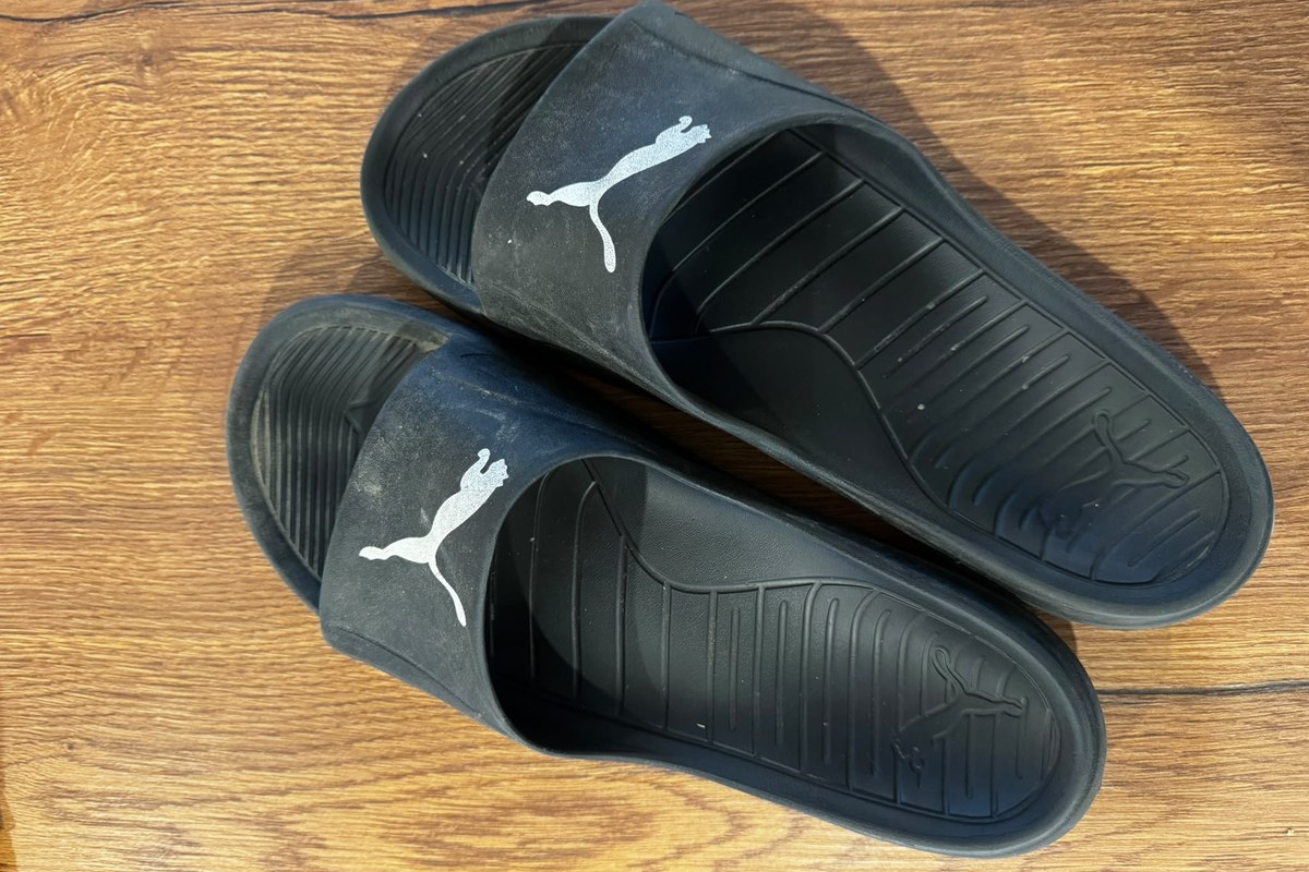 Ein Paar schwarzer Puma-Badeschuhe mit breiten Riemen und sichtbarem Fußbett