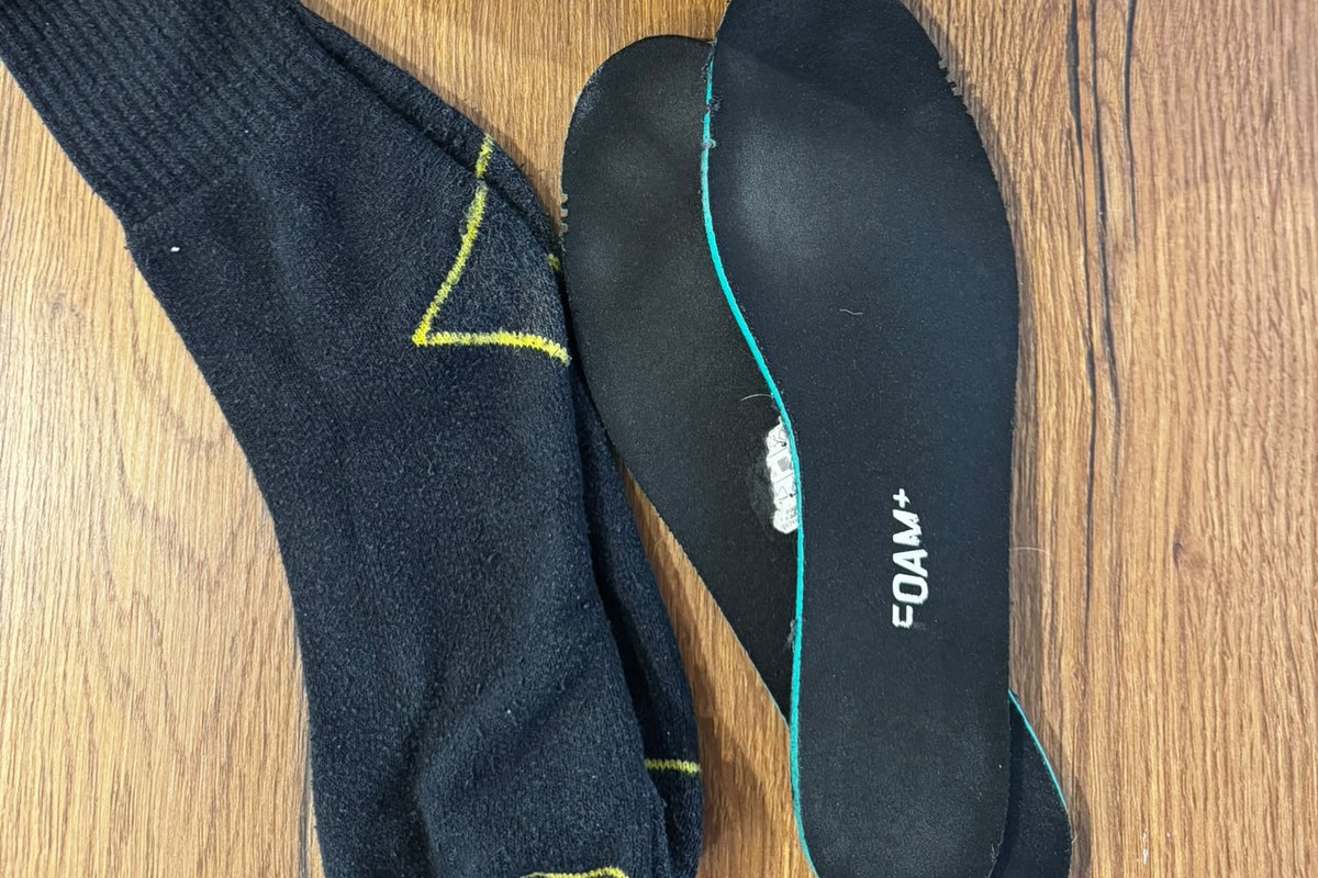 Herausgenommene schwarze Einlegesohle neben dunklen Socken